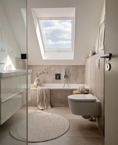 a white bathroom with a skylight above the bathtub and rug on the floor