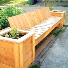 a wooden bench sitting next to a planter filled with plants