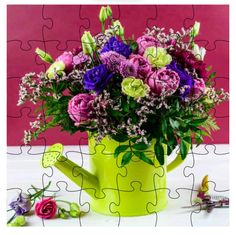 a yellow watering can filled with purple and green flowers next to a puzzle piece on a table