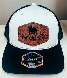 University Of Georgia, founded in 1785, it is one of the oldest public universities in the United States. This inspired us to create this original Georgia Design with the founded date and mascot on it. Cheer on the Dawgs to victory! Score a touchdown in style with the Georgia Bulldogs Leather Football Patch Hat! This unique hat features a laser engraved football pattern patch with a custom design, adding a playful touch to your game day outfit. Go Dawgs! Football Pattern, Go Dawgs, Outdoor Cap, Patch Hat, Unique Hats, University Of Georgia, Gameday Outfit, Georgia Bulldogs, Laser Engraved