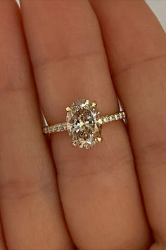 a woman's hand holding an oval diamond ring