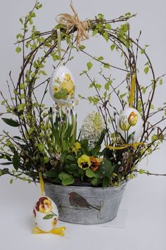 an arrangement of flowers and eggs in a bucket