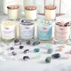 five candles with different types of rocks on the table next to each other and one candle is filled with crystals