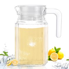 a pitcher filled with liquid next to lemons