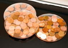 two clear bowls filled with coins on top of a black counter next to a window