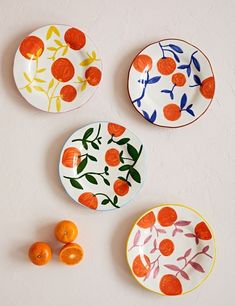 three plates with oranges on them sitting next to each other in front of a white wall