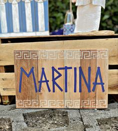 a wooden sign with the word marina written in blue ink on it next to two chairs