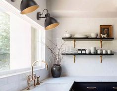 a kitchen with black cabinets and white counter tops, two hanging lights above the sink