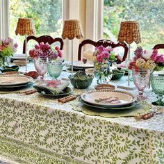 the table is set with plates and vases on it, along with other place settings