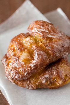 two glazed donuts sitting on top of white paper