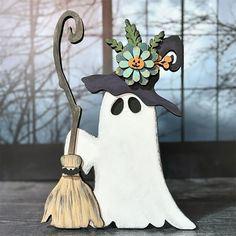 a white ghost with a black hat holding a broom and wearing a fake flower on it's head