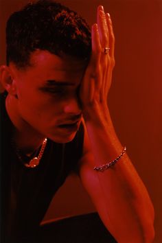 a young man holding his hands to his face while wearing a bracelet and ring on his left wrist