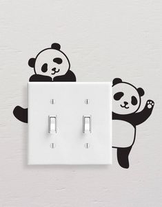 a panda bear is sitting on top of a light switch cover with its paw up