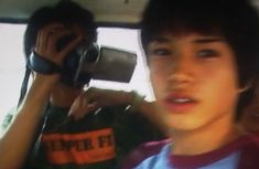 a young man sitting in the back seat of a car talking on a cell phone