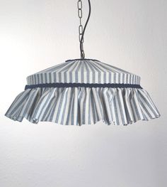 a blue and white striped lamp shade hanging from a metal hook on a wall in a room