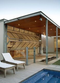 an outdoor swimming pool with chaise lounges next to it and a covered patio area