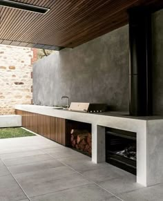 an outdoor fireplace in the middle of a patio with a stone wall and wooden ceiling