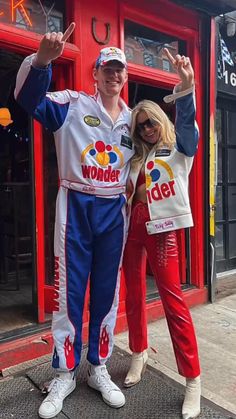 a man and woman posing for a photo in front of a store with their hands up