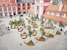 an aerial view of a courtyard with benches and trees in the center, surrounded by buildings