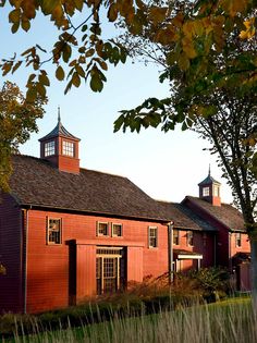 an old red barn with a clock tower on it's roof and two windows