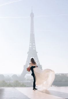 a bride and groom standing in front of the eiffel tower