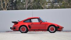 a red sports car parked in front of a white wall