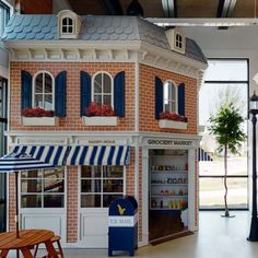 a doll house with blue shutters and white trim on the front, red brick facade