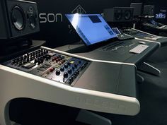 a laptop computer sitting on top of a sound mixing desk in front of some audio equipment