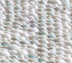 a close up view of a white and blue rug with yarn on the bottom half