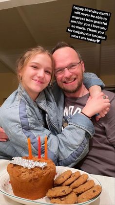 a man and woman hugging in front of a birthday cake