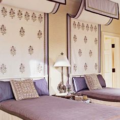 two beds in a hotel room with purple and white decor on the headboard, pillows and lamps