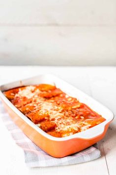 lasagna casserole in an orange dish on top of a white table