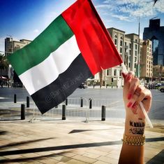 a woman holding up a flag in the middle of a street with buildings behind her