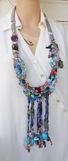 This blue tribal eclectic necklace slips on over the head and is very light, due to the fabric it is made of. It is large, at 37" around, and has 7" of beaded fabric fringe at the bottom.    The beads, that are all over this necklace, are from my collection and are made of: glass, clay, tourmaline, African stained bone, Mexican ceramics, plastic, pot metal, blue stone, and wood. I've also included a leaf charm and a grape cluster charm.    This is a statement necklace that I recently made. It has an elegant feel even though BOHO tribal in nature. I photographed it being worn on a life sized mannequin, and also next to a 12" ruler, to give a sense of size.    Please email if you have any questions about this handmade Art Necklace.    Thanks for looking! Artisan Blue Beaded Necklaces For Festivals, Blue Beaded Necklaces For Festivals, Bohemian Blue Beaded Necklace For Festivals, Blue Bohemian Beaded Necklace For Festivals, Artisan Beaded Necklaces With Boho Collar For Festivals, Artisan Blue Beaded Necklace For Festival, Eclectic Handmade Beaded Necklaces For Festivals, Eclectic Handmade Beaded Necklace For Festivals, Blue Hippie Beaded Necklaces