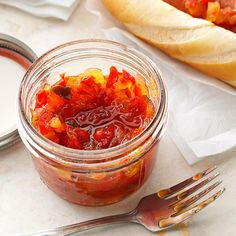 a glass jar filled with food sitting on top of a table next to a fork