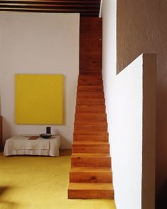 there is a yellow painting on the wall next to some stairs in this living room