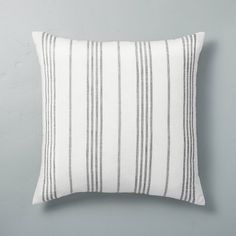 a white and blue striped pillow sitting on top of a gray wall