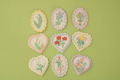 six embroidered heart shaped flowers on a green background