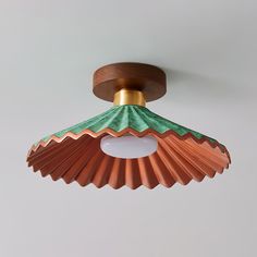 a ceiling light with an orange and green shade on it's top hanging from the ceiling