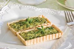 two small tarts on a white plate with green garnish and sprigs