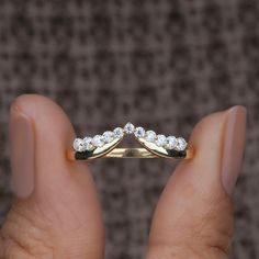 a woman's hand holding a gold wedding band