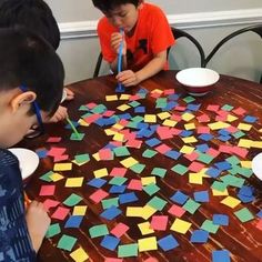 three boys are sitting at a table with colored post - it notes on the table