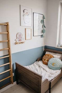 a small bed in a room with pictures on the wall and a ladder hanging above it