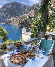 an image of a table with food and drinks on it in front of the ocean