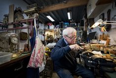 an older man sitting in a workshop working on something