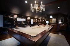 a pool table in the middle of a room with chandeliers hanging from the ceiling