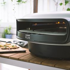 a toaster oven sitting on top of a wooden table next to a cutting board