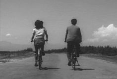 two people riding bikes down a dirt road