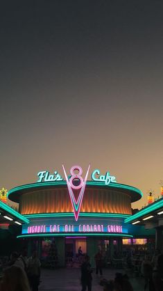 people are standing in front of a large building with neon signs on the side of it