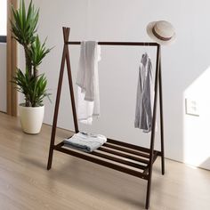 an ironing board with clothes hanging on it and a potted plant next to it